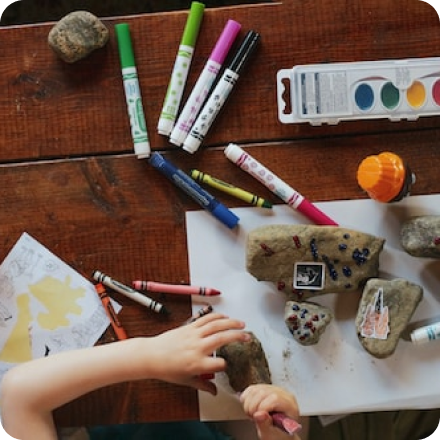 manos de niño pintando rocas